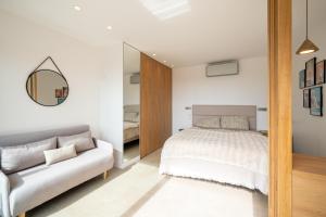 a bedroom with a bed and a mirror and a couch at Appartement luxe vue mer et collines avec piscine in Mandelieu-La Napoule