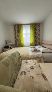 two beds in a bedroom with green curtains at "Глиняна хатинка" in Beloberëzka