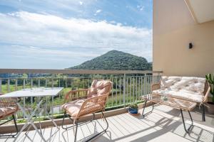 a balcony with chairs and a table and a mountain at Appartement luxe vue mer et collines avec piscine in Mandelieu-La Napoule