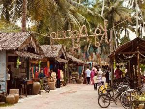 a group of people walking around a market with palm trees at Homestay Santai Bertam in Kepala Batas