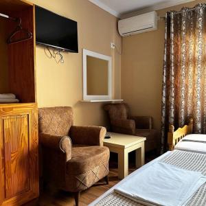 a bedroom with a bed and a chair and a tv at Vila Park Hotel 1 in Tirana