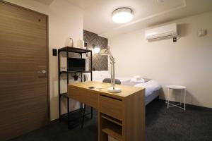 a room with a bed and a desk with a lamp at TAKETO STAY PREMIERE SAPPORO EKi in Sapporo +78 photos