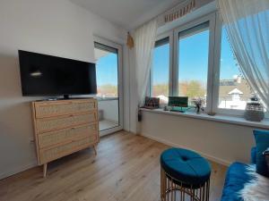 a living room with a flat screen tv and two windows at Angel's Home in Dunajská Streda