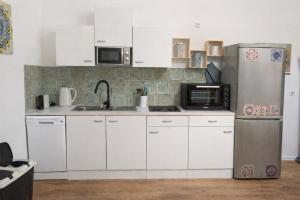 a kitchen with white cabinets and a stainless steel refrigerator at Natururlaub Eifel-Mandala Feriewohnung in Kall