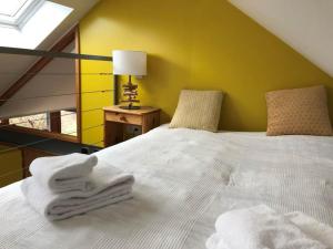 a bedroom with a white bed with a yellow wall at Au Grand Babin - Namur in Namur