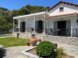 a white house with a table and chairs in a yard at Ninemo Residences Skiathos in Achladies
