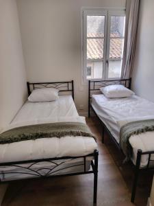 two twin beds in a room with a window at Logement 2 cité de caractère in Mallièvre