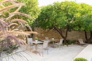 a patio with two tables and chairs and trees at Rose Iconic Rooms in Lecce