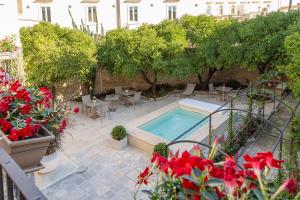 a patio with a swimming pool and some red flowers at Rose Iconic Rooms in Lecce