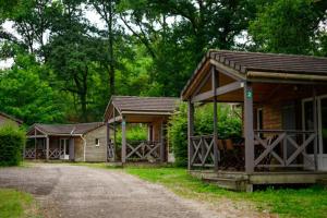a couple of small buildings with trees and a road at Camping Les Aubazines in Bort-les-Orgues