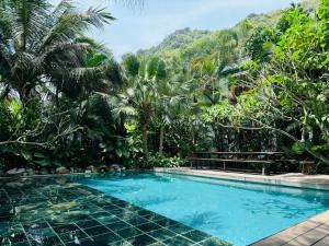 a swimming pool in a resort with palm trees at The Wooden Gate in Xuân Sơn