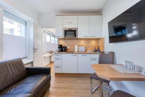 a kitchen with a couch and a table in a room at Alte Teestube 69 2 Raum in Norderney +5 photos