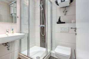 a bathroom with a shower and a toilet and a sink at Alte Teestube Schmidt 68 in Norderney