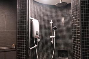 a bathroom with a shower with black tile on the wall at Love Inn Hotel Kuchai Lama in Kuala Lumpur
