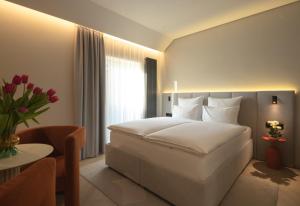 ein Hotelzimmer mit einem weißen Bett und einem Tisch in der Unterkunft Hotel Laudon in Uschhorod