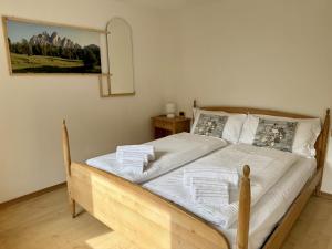 a bedroom with a wooden bed with white sheets and pillows at Appartamento Il Conte di Avoscano in Piaia