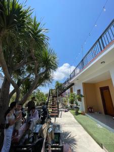 a group of people sitting on benches next to a building at Sun Homestay Doclet in Doc Let