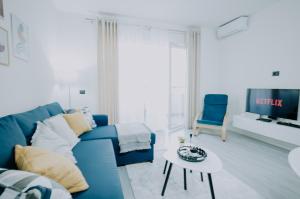 a living room with a blue couch and a tv at Elrea Living 2 Central 1BR with Dajti & Skyline View in Tirana