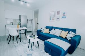 a living room with a blue couch and a kitchen at Elrea Living 2 Central 1BR with Dajti & Skyline View in Tirana