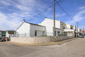ein weißes Haus an einer Straßenseite in der Unterkunft Stay in Corroios Near Lisbon and 15 Min from the Beach - Casa Acolhedora em Corroios Perto de Lisboa e da Praia in Corroios