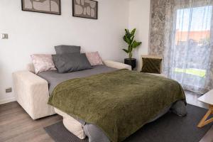 a bedroom with a bed and a couch and a window at L'Écrin Marguerite - Strasbourg-CMCO-Zénith-Espace Européen de l'Entreprise in Schiltigheim