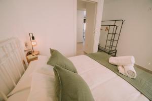 a bedroom with a bed with white sheets and green pillows at Casa Aula Minerva Lumen 3 Dormitorios in Almedinilla
