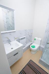 a white bathroom with a sink and a toilet at Nura Hotel in Shymkent
