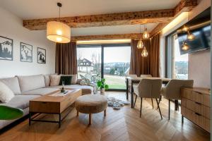 a living room with a couch and a table at Allure Chalet, z prywatnym jacuzzi, z widokiem na góry in Dzianisz