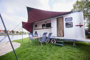 a rv with a table and chairs on the grass at Glampervan Julietta in Den Bosch