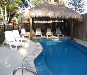 a swimming pool with chairs and a thatch hut at Palm Beach Caravan Park in Sanctuary Point
