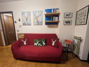 a red couch with two cats pillows on it at Appartamento Cedro - Centro Aprica - Park - WiFi in Aprica