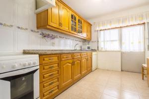 a kitchen with wooden cabinets and a white appliance at Cozy Room in Corroios Near Beach & Lisbon - Quarto Acolhedor em Corroios Perto da Praia e Lisboa in Corroios