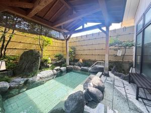 a swimming pool with rocks and a building at Hotel Livemax Tagajo in Tagajo