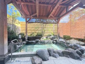 a swimming pool in a garden with rocks around it at Hotel Livemax Tagajo in Tagajo