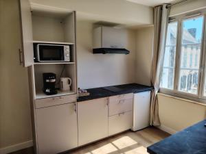 a small kitchen with white cabinets and a microwave at Logement 2 cité de caractère in Mallièvre