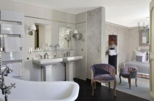 a woman standing in a bathroom with a sink and a tub at Logis Hôtels Restaurant Les 3 Rois in Issoudun +55 photos