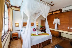 a bedroom with a canopy bed with white drapes at Desamuda Village by Pertama Stay in Seminyak