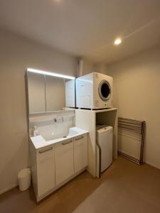 a small kitchen with a microwave and a sink at 伊都伎-Itsuki- 宮島口の貸切一軒家 世界遺産宮島へ渡る港まで徒歩圏内 最大16名 in Hatsukaichi
