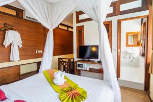 a bedroom with a bed and a tv and a bathroom at Desamuda Village by Pertama Stay in Seminyak