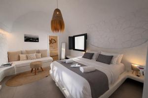 a bedroom with a large white bed and a couch at Rosaviglia Luxury Villa - an Oia Private Hideaway in Oia +17 photos