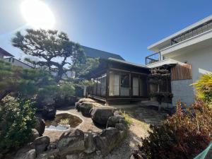 a house with a pond in front of a house at 伊都伎-Itsuki- 宮島口の貸切一軒家 世界遺産宮島へ渡る港まで徒歩圏内 最大16名 in Hatsukaichi