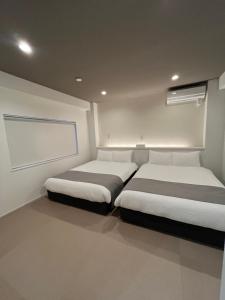 a bedroom with two beds and a window in it at 伊都伎-Itsuki- 宮島口の貸切一軒家 世界遺産宮島へ渡る港まで徒歩圏内 最大16名 in Hatsukaichi
