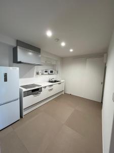 a kitchen with white cabinets and a white refrigerator at 伊都伎-Itsuki- 宮島口の貸切一軒家 世界遺産宮島へ渡る港まで徒歩圏内 最大16名 in Hatsukaichi +24 photos