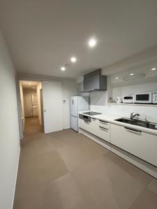 a white kitchen with a sink and a refrigerator at 伊都伎-Itsuki- 宮島口の貸切一軒家 世界遺産宮島へ渡る港まで徒歩圏内 最大16名 in Hatsukaichi
