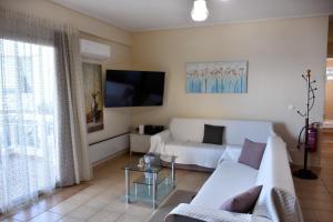 a living room with a white couch and a tv at Seaside apartment platana kimis evoia in Kymi