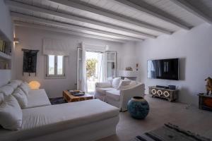 a living room with white furniture and a tv at Villa Moon with Private Swimming Pool in Aspro Chorio Paros