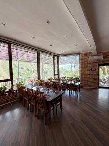 a dining room with a table and chairs and windows at Shamshod Mountain Resort in Yangiobod