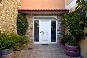 a white door in a brick building with plants at Seaside apartment platana kimis evoia in Kymi