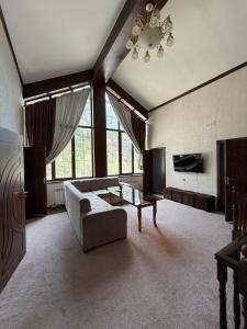 a large living room with a couch and a tv at Shamshod Mountain Resort in Yangiobod