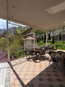 a patio with tables and chairs and a view of a hill at Shamshod Mountain Resort in Yangiobod